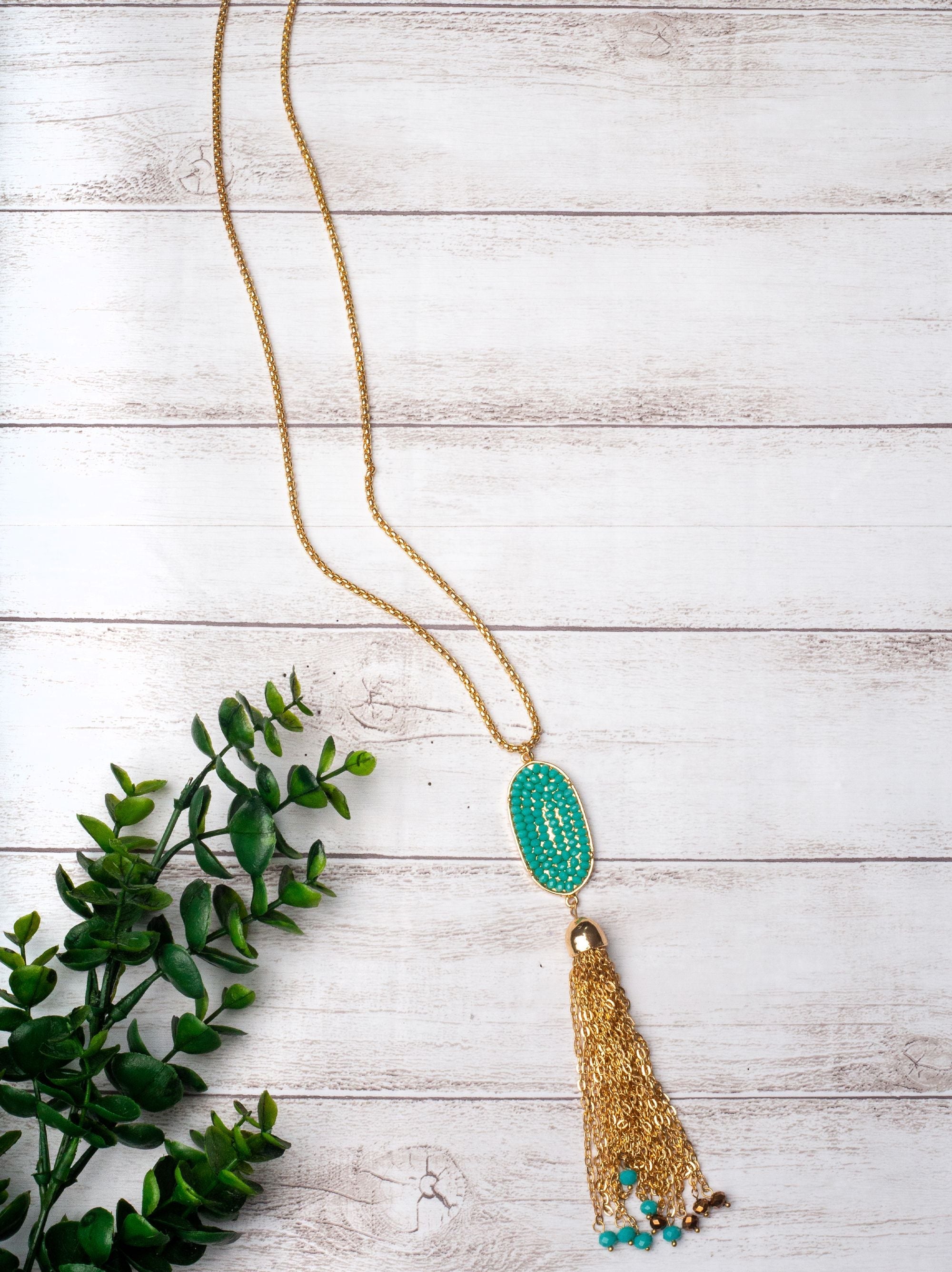 A LITTLE SPARKLE TURQUOISE CRYSTAL OVAL PENDANT TASSEL ON A GOLD NECKLACE